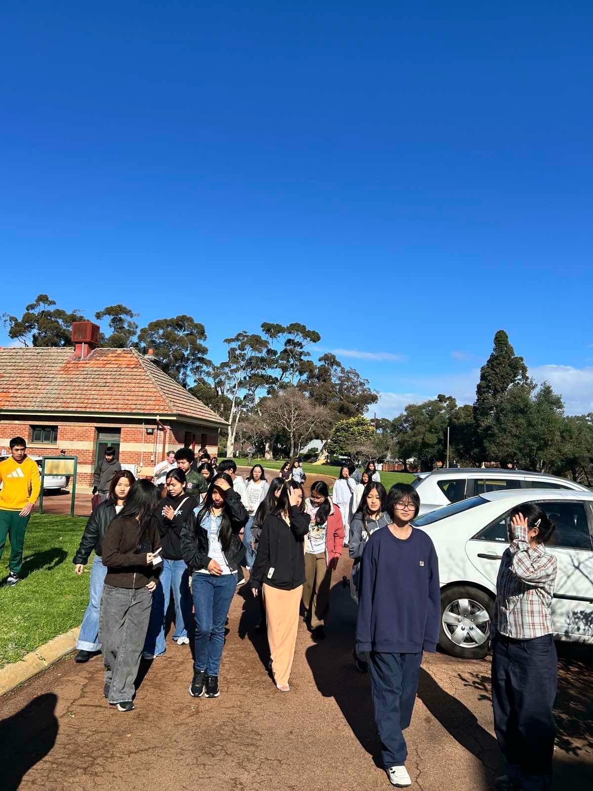Young Burmese Catholic community members walking together outdoors in Western Australia.